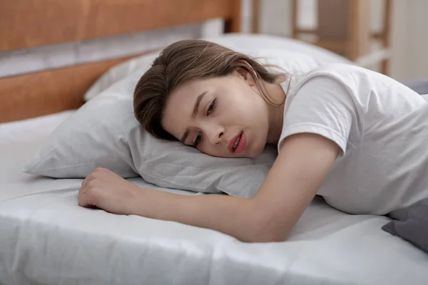 Genç bir kadın yatağında tek başına yatıyor, sevdiğinin yasını tutuyor, ağır depresyondan muzdarip. — Stok fotoğraf