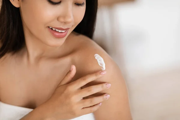 Primer plano de mujer asiática envuelta en toalla hidratando su piel — Foto de Stock