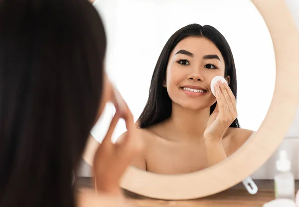Lächelnde asiatische Frau reinigt ihr Gesicht mit Wattepads — Stockfoto