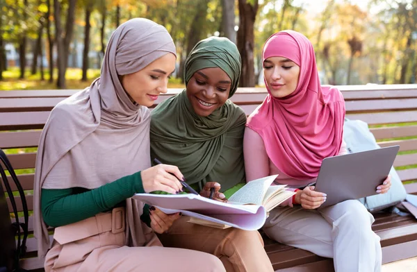 Tres estudiantes musulmanas aprenden juntas usando la computadora sentadas al aire libre — Foto de Stock