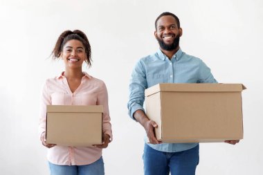 Neşeli, genç, Afro-Amerikan karı ve koca oturma odasında karton kutular taşıyorlar yeni evlerinde, boş alanlarda. Çift boş odada taşınmayı sever. Taşınma, kiralama ve satın alma