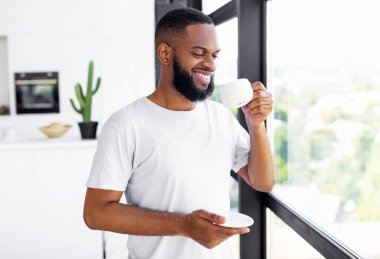 Gülümseyen, Afro-Amerikan Keyifli Sabahın Portresi, Evdeki sıcak kahve içen, elinde fincan ve tabak tutan, favori içecekle başlayan,