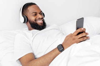 Kulaklıklı, sakallı, akıllı telefonuyla yazı yazan, müzik dinleyen ve yatak odasındaki beyaz yatakta komik videolar izleyen neşeli, Afro-Amerikan bir adam. Dinlen ve rahatla, hafta sonu ve boş zaman