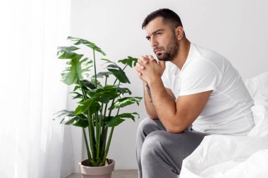 Dalgın üzgün yorgun milenyum kaslı Avrupalı erkek yatak odasının içinde depresyon ve stresten yatıyor. Covid-19 karantinası sırasında sorunlar, işsizlik ve kendini izole etme