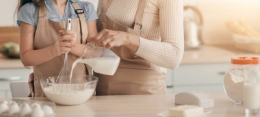 Aile tarifi. Neşeli büyükanne ve torunu mutfakta birlikte yemek pişiriyorlar. Şirin küçük kız evde büyükannesiyle kurabiye için öksürüyor, Bayan bowling için yeni şeyler ekliyor, süt döküyor.