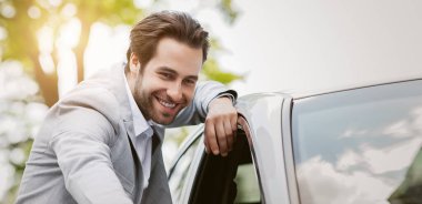 Yeni araba seçmek, galeriden araba almak, kira ve insani duygular. Menajer veya satıcı işi. Gülümseyen bin yıllık yakışıklı beyaz adam modern ulaşım araçlarına bakıyor.