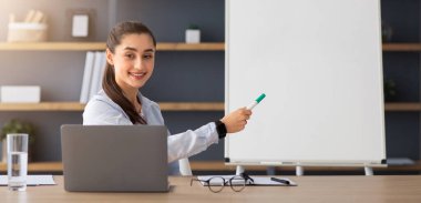 Yeni bir dil öğren, çevrimiçi öğrenim ve kendini izole etme konusunda modern eğitim al. Gülümseyen bin yıllık Arap bayan öğretmen ya da hoca kurallara uyuyor, iç dizüstü bilgisayarla masada oturuyor.