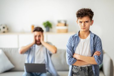 Nesiller boyu yanlış anlaşılma. Babam arka planda dizüstü bilgisayarda çalışırken, kanepede otururken, elleri çapraz duran ve kameraya bakan bir çocuk gücenmiş.