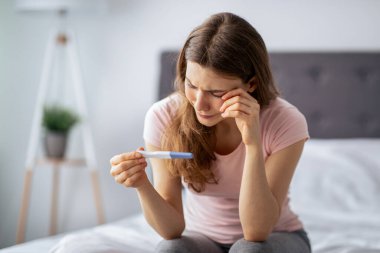 Hamilelik testine bakan mutsuz, beyaz bir kadın evde yatakta ağlıyor. Beklenmedik bir doğumla karşı karşıya kalan ya da çocuk sahibi olamayan üzgün genç bir bayan. Annelik sorunu kavramı