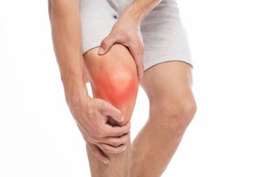 Diz ağrısından muzdarip tanınmayan genç beyaz bir adam. Kırmızıyla işaretlenmiş, beyaz arka planda izole edilmiş, el ele hassas noktalara baskı yapıyor. Eklem iltihabı, spor sakatlığı, sağlık hizmetleri ve sorunlar