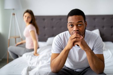 Üzgün siyah adam yatakta, derin düşüncelere dalmış, aile sorunlarıyla boğulmuş, arka plandaki tatminsiz kız arkadaşı. İlişkilerinde ya da cinsel sorunları olan çok ırklı aşıklar