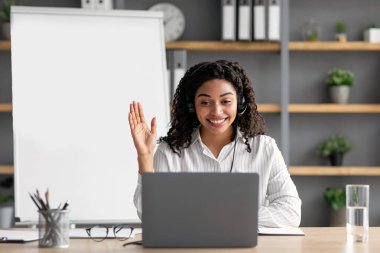 Video görüşmesi, toplantı, evde çalışma, uzaktan ders, covid-19 salgını. İyi ki kulaklıklı genç Afrikalı Amerikalı kadın özel öğretmen el sıkışıyor, öğrenciyle konuşuyor, bilgisayarın içerideki web kameralarına bakıyor.