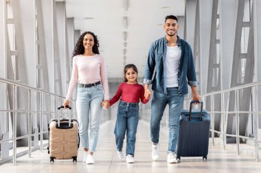 Tatile hazırım. Havalimanı Terminali 'nde çantalarla yürüyen mutlu bir Orta Doğulu aile küçük kızı olan gülümseyen bir Arap ebeveyn el ele tutuşuyor, birlikte seyahat etmekten keyif alıyor,