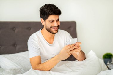 Hafta sonu sabah tatili. Yatakta akıllı telefon kullanan mutlu bir Arap. Adam online oyunlar oynuyor, internette geziniyor, sabahları cep telefonuyla sohbet ediyor. Akıllı telefon için yeni mobil uygulama