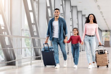 Sonunda tatil zamanı. Havalimanında yürürken el ele tutuşan heyecanlı gülümseyen Arap ailesi, Mutlu Ebeveynler ve Küçük Kız Terminal Salonu 'ndan geçerken bavullarını taşıyarak yaklaşan yolculuğun tadını çıkarıyorlar.