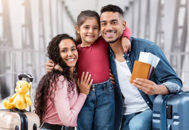 Tatile hazırım. Havalimanında üç kişilik mutlu bir Arap aile portresi, Orta Doğulu ebeveynler ve bavulları ve pasaportları olan şirin bir kadın çocuk terminalde uçmayı bekliyor.