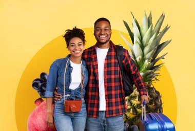 İki genç yetişkin taze meyvelerle dolu canlı bir arka plana gülümsüyor. Neşe saçıyorlar, sağlıklı yaşam tarzlarını ve besleyici yiyeceklere olan sevgilerini sergiliyorlar..