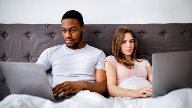 Odaklanmış siyah adam ve Kafkasyalı karısı yataklarında dizüstü bilgisayar kullanıyorlar, işle ya da evde çalışmakla meşguller. Gadget bağımlılığından muzdarip genç bir çift. Birbirlerine dikkat etmiyorlar.