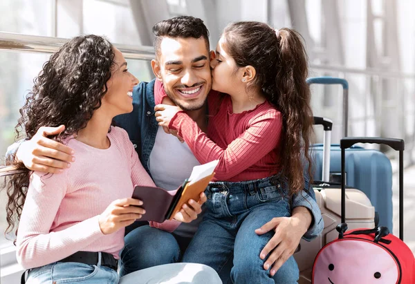 Güzel, gülümseyen bir Arap ailenin, kızıyla birlikte havaalanında vakit geçiren neşeli bir Orta Doğulu ebeveyn ve tatlı bir çocuğun uçuşu beklerken eğlendiği portresi.