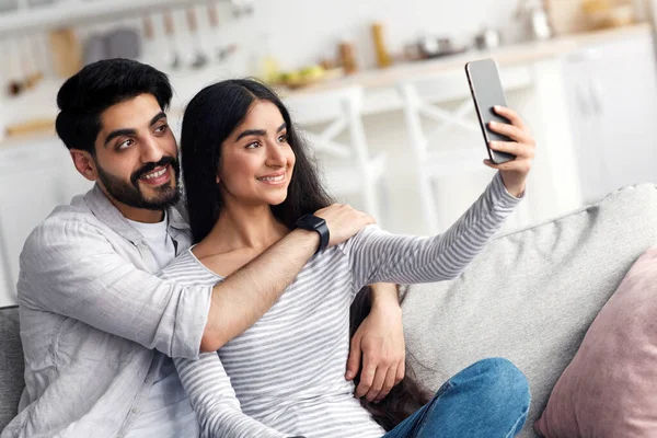 Evde selfie 'ler, tarih, olumlu duygular, yeni uygulama ve kendini izole etme. İyi ki genç ve güzel bir Arap karı koca kucaklaşıp fotoğraf çekiyorlar. Oturma odasının içindeki akıllı telefonlarda web kameralarına bakıyorlar.