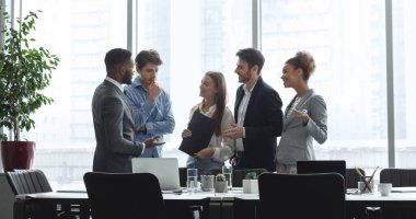 Çeşitli yönetim ekipleri konferans odasında konuşuyor, ofis pencereleri ve panorama hakkında tartışıyorlar.