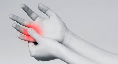 Elindeki acıdan muzdarip genç bir kadın acı veren parmağına masaj yapıyor, tek renkli panorama.