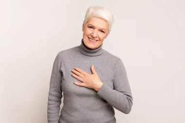 Minnettar yaşlı bayan elini göğsüne koydu, minnettarlığını ve minnettarlığını ifade etti. Boş alanı olan hafif stüdyo arkaplanı