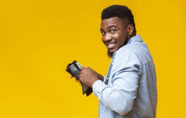 Yankesicilik konsepti. Çalıntı cüzdan taşıyan siyah bir hırsız ve sarı stüdyo geçmişinde para sayan bir hırsız.