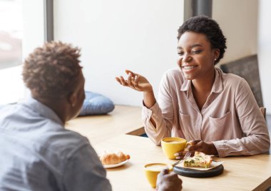 Neşeli siyah çift modern kahve dükkanında ilk buluşmada eğleniyor.