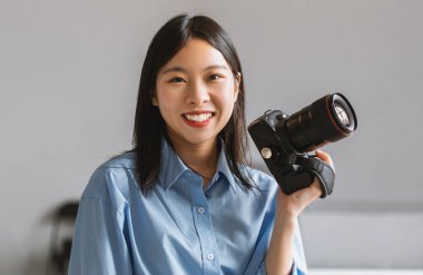 Profesyonel fotoğrafçı. Teçhizatlı gülümseyen Asyalı kadın portresi ve İçişleri Bakanlığı 'nda kameraya gülümsüyor. Fotoğraf makinesiyle poz veren bir kadın. Fotoğraf Konsepti