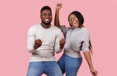 Siyahi çiftin iyi haberleri var. Pembe stüdyo arka planında başarıyı kutluyorlar. Yumruk sallıyorlar ve dans ediyorlar.