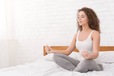 Meditasyon. Genç bin yıllık kadın yatakta lotus pozisyonu yatakta oturup meditasyon. Anti-stres yoga, kopya alanı uygulamak kız