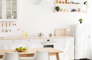 Yenilemeden sonra yeni bir İskandinav tasarımı. Farklı aletleri olan beyaz ve ahşap mobilyalar, raflarda mutfak gereçleri, küçük buzdolabının yanında tahta kesme, boş alan.