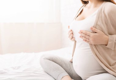 Hamile bir kadın göğsünde acı hissediyor, kendine masaj yapıyor, boş alanı olan bir panorama.