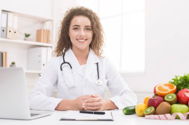 Kilo kaybı ve doğru beslenme. Ofiste diyet planı üzerinde çalışan dietisyen, kameraya gülümseyen, boş alan