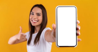 Tavsiye ederim. Elinde beyaz bir ekranla akıllı telefonu tutan gülümseyen bir kadının portresi. Cihazı gösteriyor ve işaret ediyor. Model için boş alanı olan aygıta odaklan, afiş