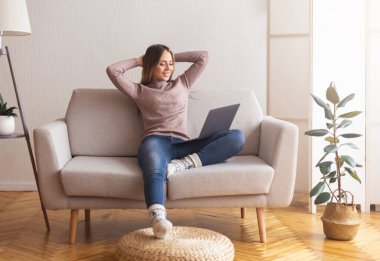 Sıcak bir iş yeri. Rahatlamış serbest çalışan kız evde dizüstü bilgisayarla çalışıyor.