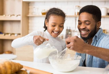 Sevimli Afro-Amerikan Kız Mutfakta Kase Into Süt Dökme, baba hamur karıştırma, kopya alanı