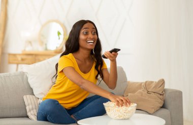 Genç siyahi kadın boş zamanlarını televizyon izleyerek ve evdeki kanepede patlamış mısır yiyerek geçiriyor. Uzaktan kumandalı güzel Afrikalı Amerikalı kadın oturma odasında ilginç bir film izliyor.