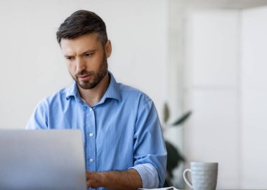 İşyerindeki dizüstü bilgisayarda çalışan konsantre işadamı, bilgisayar ekranına bakan ve klavyeye yazan erkek girişimci, rapor dolduran, e-postaları cevaplayan, yönetim projesi, kopyalama alanı