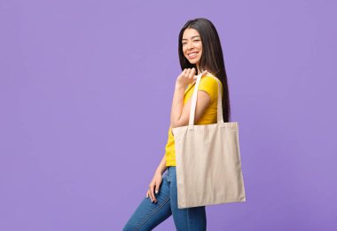 Çevre dostu yaşam tarzı. Neşeli Asyalı Kız Poz Veriyor Boş Tote Eko Torbası Mor Stüdyo Arkaplanı Üzerinde, Boşluğu Kopyala