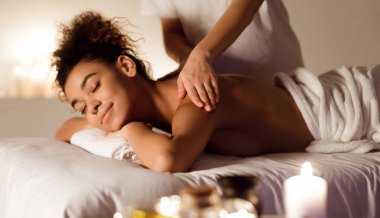 Milenyum Afro Kadını kaplıcada sırt masajından zevk alıyor, kapalı gözlerle rahatlıyor.