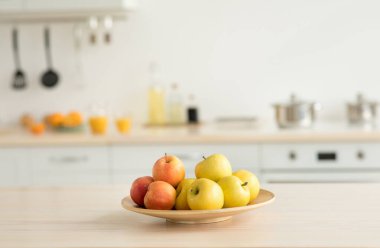 En az modern mutfağın içinde yiyecek ve içecekler. Tabaktaki taze elmalar beyaz mobilyalar ve modern yemek odasının basit tasarımı. Gün ışığında tabaklar ve beyaz mobilyalar. Boş uzay.