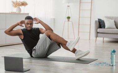 Abs Egzersiz. Afro-Amerikalı adam evde dizden dize karın çatırtısı yapıyor. Laptopta egzersiz yapıyor. Online Eğitim Konsepti. Spor Yaşam Tarzı ve Vücut Geliştirme. Seçici Odaklanma