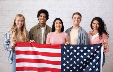Göçmenlik, taşınma ve yurtdışında eğitim. Neşeli genç uluslararası öğrenciler kameraya bakıp öğrenmeye hazırlar. Beyaz tuğlalı arka planda, fotokopi alanında, stüdyo çekimlerinde.