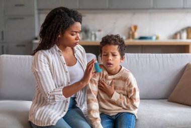 Saldırıyı önlüyorum. Bakıcı anne, hasta oğluna astım spreyi veriyor. Genç anneyi seviyor. Hasta, reşit olmayan erkek çocuğa bakıyor.
