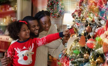 Mutlu Afro-Amerikan ailesi, evde Noel ağacı süslüyorlar, birlikte tatilleri kutluyorlar..