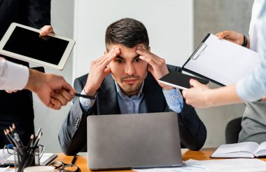 Çoklu görev. Dizüstü bilgisayarın başındaki stresli işadamı modern ofiste oturmaktan yoruldu..