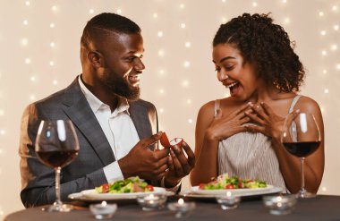 Sevgililer Günü 'nde evlilik teklifi. Siyahi bir adam, restoranda yemek yerken sürpriz yapan güzel karısına evlenme teklif ediyor.