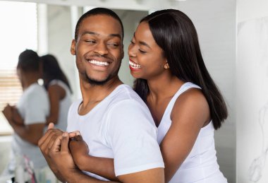 Banyoda aynanın yanında kucaklaşan mutlu Afro-Amerikalı çiftin portresi, neşeli siyah milenyum eşleri sarılıyor ve gülüyor, sabahları birlikte vakit geçiriyorlar, yakınlaşıyorlar.